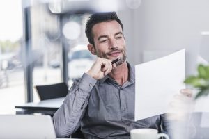 Businessman sitting in office, reading a letter