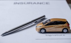 Car and pen on insurance documents. Car insurance concept.
