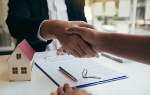 Home sales agents and buyers work on signing new homes and shaking hands.